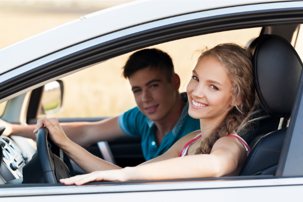 a pair of young people driving a car