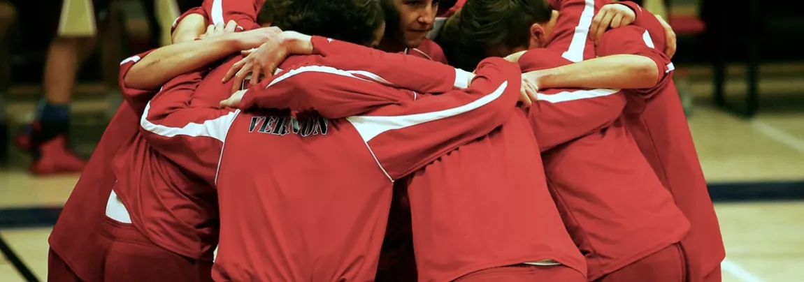 an image of a team wearing red jerseys huddling before practice 