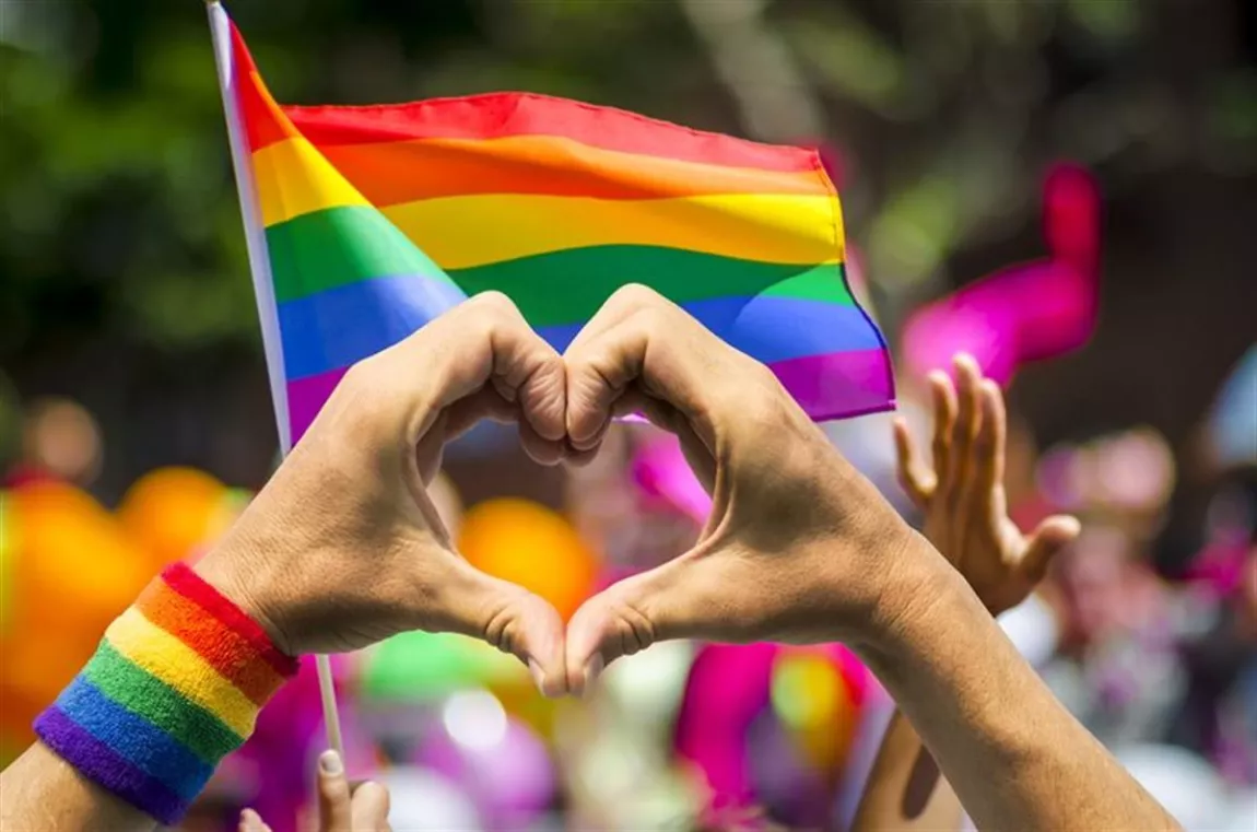 Rainbow flag with heart shaped hand gesture